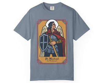 May include: A blue t-shirt with a graphic of St. Michael the Archangel. The illustration shows a figure with a sword and shield, within a decorative border. The text "St. Michael the Archangel" is at the bottom.
