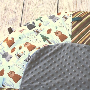 Puede incluir: Una alfombra de juego redonda, gris y blanca con estampado de animales del bosque. La alfombra tiene una superficie suave y texturizada, ideal para beb&eacute;s y ni&ntilde;os peque&ntilde;os.