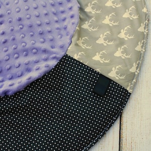 May include: A round, multi-colored play mat with a purple, black and white polka dot, and gray fabric with white deer silhouettes.
