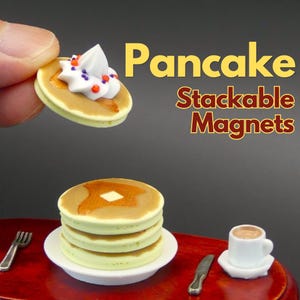 以下が含まれることがあります： ミニチュアのパンケーキ型スタッキングマグネットセット。1枚のパンケーキには白いホイップクリームとカラフルなスプリンクルがトッピングされています。バターがのった3枚重ねのパンケーキが白い皿にのっており、横には小さな白いコーヒーカップとカトラリーが添えられています。