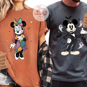 Op de afbeelding: Twee T-shirts met Disney-personages in Halloween-kostuums. E&eacute;n is een oranje shirt met Minnie Mouse verkleed als Sally uit The Nightmare Before Christmas. De andere is een antracietkleurig shirt met Mickey Mouse als Jack Skellington.