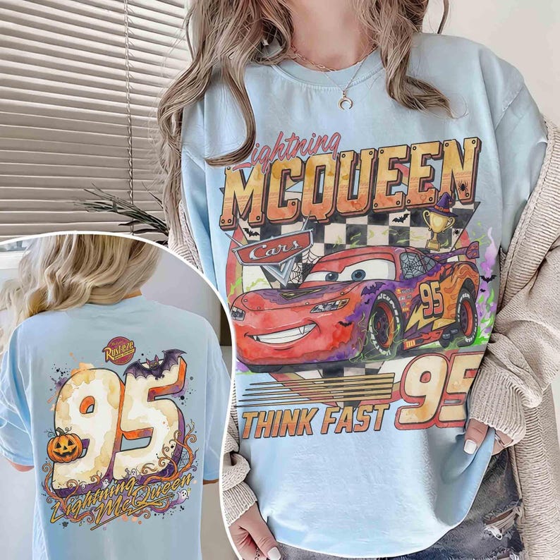 May include: A light blue crewneck sweatshirt featuring a graphic of Lightning McQueen from the movie Cars with Halloween elements, including a trophy, bats, and the text Lightning McQueen and Think Fast. The back shows a large 95 with a pumpkin.