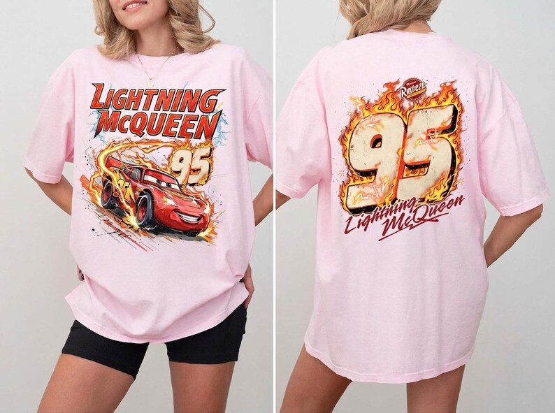 May include: A light pink t-shirt featuring a graphic of the red race car Lightning McQueen with the text Lightning McQueen and 95 on the front, and a large 95 graphic surrounded by flames with the text Lightning McQueen on the back.