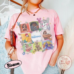 Puede incluir: Camiseta rosa claro con una cuadr&iacute;cula de personajes de Moana. La camiseta tiene cuello redondo y mangas cortas. La palabra "Moana" est&aacute; impresa en el centro de la cuadr&iacute;cula. La camiseta tambi&eacute;n tiene los textos "Blossom" y "Tina Love Art Clothing Shop".