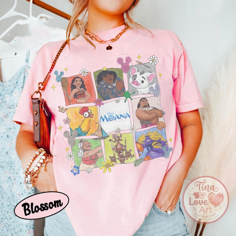 Puede incluir: Camiseta rosa claro con una cuadr&iacute;cula de personajes de Moana. La camiseta tiene cuello redondo y mangas cortas. La palabra "Moana" est&aacute; impresa en el centro de la cuadr&iacute;cula. La camiseta tambi&eacute;n tiene los textos "Blossom" y "Tina Love Art Clothing Shop".