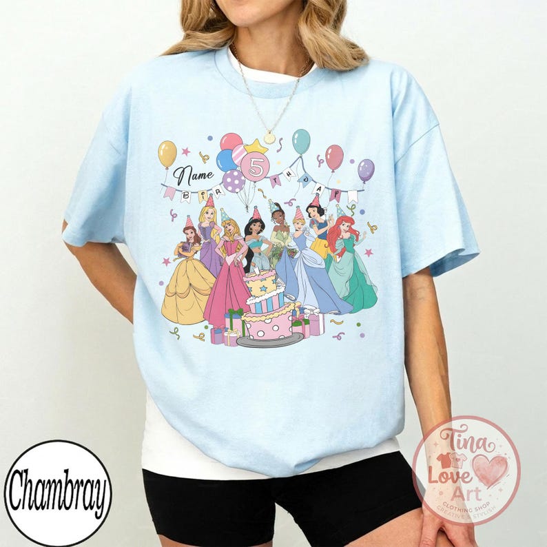 May include: Light blue t-shirt featuring a group of cartoon princesses around a birthday cake. The shirt has the word "Name" above the princesses and a number "5" in a balloon. Balloons and party hats are also included in the design.
