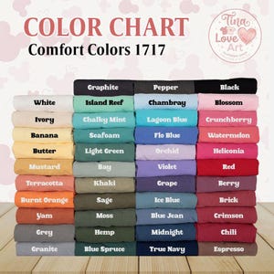 May include: Color chart of Comfort Colors 1717. The chart displays a variety of folded fabric samples in an array of colors, including white, black, blue, green, and red. The text "COLOR CHART" and "Comfort Colors 1717" are at the top.