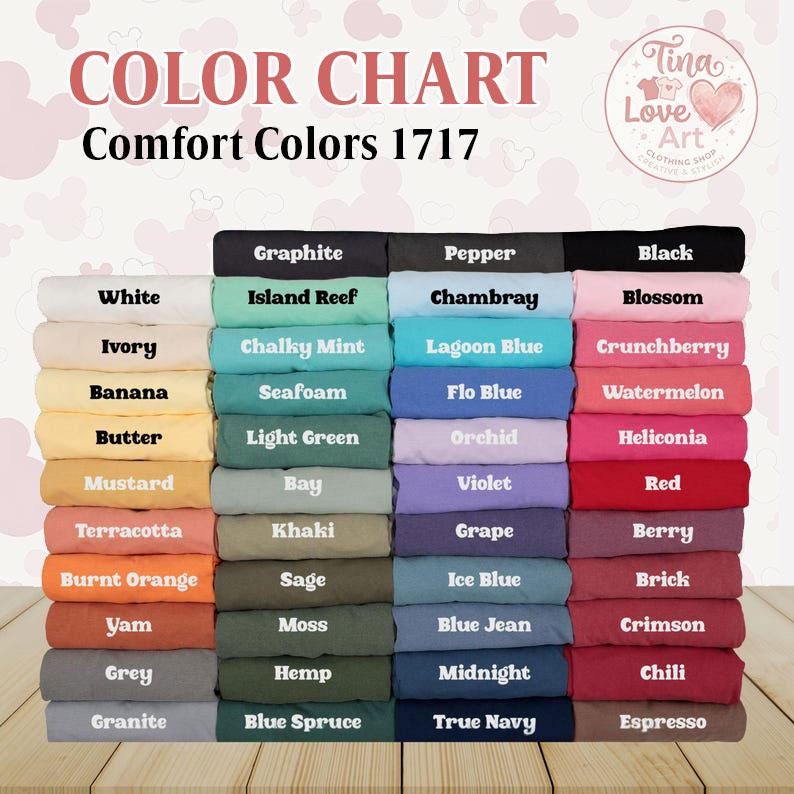 May include: Color chart of Comfort Colors 1717. The chart displays a variety of folded fabric samples in an array of colors, including white, black, blue, green, and red. The text "COLOR CHART" and "Comfort Colors 1717" are at the top.