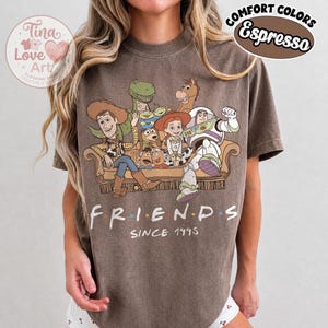 Peut inclure: Un t-shirt &agrave; manches courtes couleur espresso avec un imprim&eacute; repr&eacute;sentant les personnages de Toy Story assis sur un canap&eacute;. Sous le canap&eacute;, le texte indique FRIENDS SINCE 1995. Le t-shirt pr&eacute;sente un aspect d&eacute;lav&eacute; et un col rond.