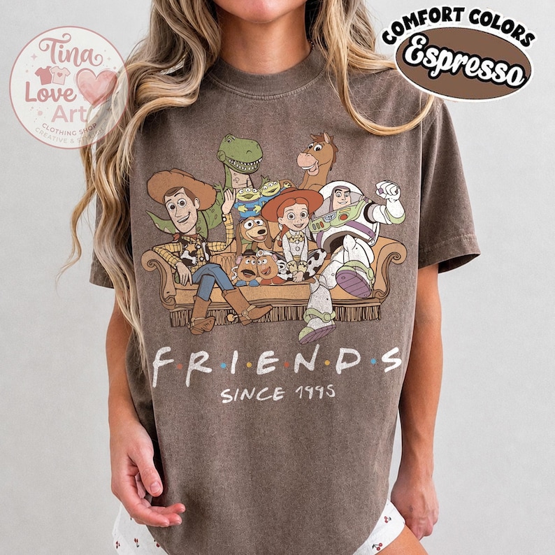 Peut inclure: Un t-shirt &agrave; manches courtes couleur espresso avec un imprim&eacute; repr&eacute;sentant les personnages de Toy Story assis sur un canap&eacute;. Sous le canap&eacute;, le texte indique FRIENDS SINCE 1995. Le t-shirt pr&eacute;sente un aspect d&eacute;lav&eacute; et un col rond.