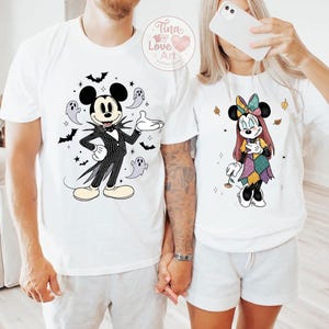 Op de afbeelding: Witte T-shirts met Halloween-thema Mickey Mouse en Minnie Mouse ontwerpen. Mickey is verkleed als Jack Skellington, omringd door vleermuizen en geesten. Minnie Mouse draagt een patchwork jurk en een strik. Ideaal voor koppels.