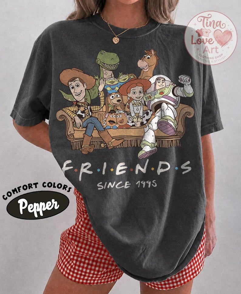 Peut inclure: Un t-shirt gris anthracite &agrave; manches courtes avec une impression graphique de personnages de Toy Story assis sur un canap&eacute;, accompagn&eacute; du texte "F.R.I.E.N.D.S" et "SINCE 1995" imprim&eacute; sous l'illustration. Le t-shirt a un col rond et une coupe d&eacute;contract&eacute;e.
