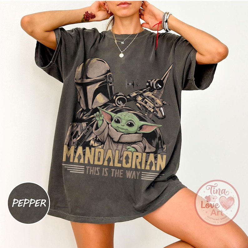 Pu&ograve; includere: T-shirt grigio scuro con grafica di The Mandalorian e Grogu di Star Wars. Il design include la scritta "MANDALORIAN THIS IS THE WAY" in stile vintage. La maglietta ha maniche corte e una vestibilit&agrave; ampia.