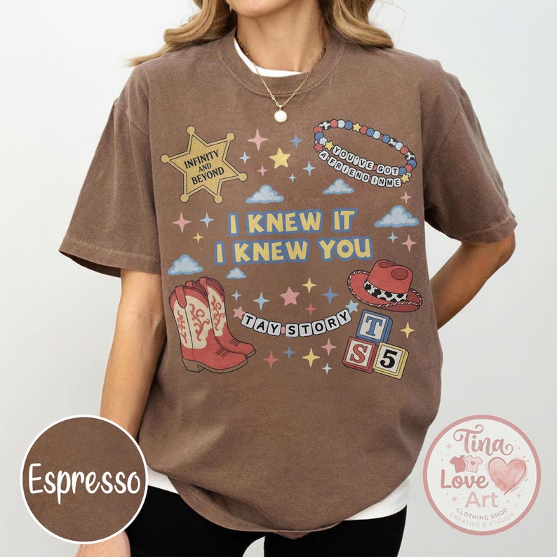 May include: A brown short-sleeve t-shirt featuring a graphic print with a yellow star labeled Infinity and Beyond, a beaded bracelet, a red cowboy hat, alphabet blocks, and the text I Knew It I Knew You and Tay Story with colorful stars.