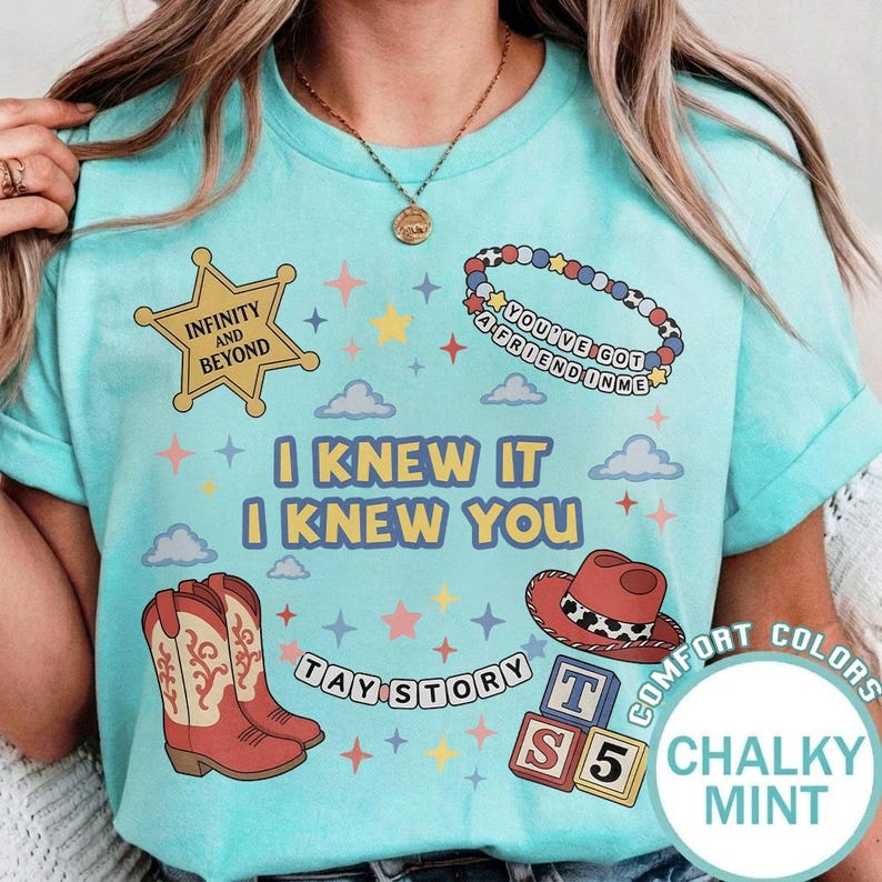 May include: A mint green t-shirt featuring a graphic print with a yellow sheriff star labeled Infinity and Beyond, a beaded bracelet reading You've Got a Friend in Me, cowboy boots, a red hat, alphabet blocks, and the text I Knew It I Knew You.