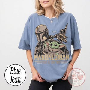 Pu&ograve; includere: T-shirt azzurra con una grafica di The Mandalorian e Grogu, un'astronave e la scritta "MANDALORIAN. This is the way." La maglietta ha maniche corte e una vestibilit&agrave; ampia.