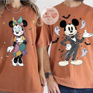 Op de afbeelding: Twee oranje T-shirts met Disney-figuren voor Halloween. E&eacute;n shirt toont Minnie Mouse in een patchwork jurk, de andere Mickey Mouse als Jack Skellington, omringd door vleermuizen en geesten. Onderdeel van een Halloween collectie.