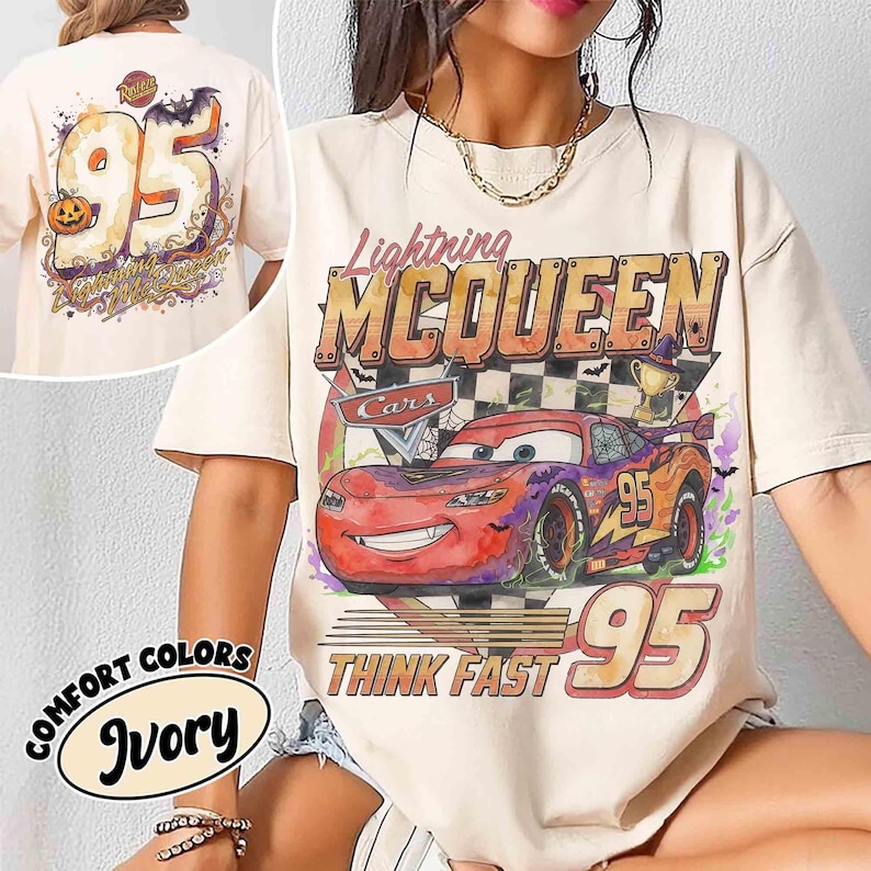 May include: An ivory t-shirt featuring a graphic print of the character Lightning McQueen from the movie Cars. The design includes the text Lightning MCQUEEN, Think Fast, and the number 95, with a checkered flag, a trophy, and spider web accents.