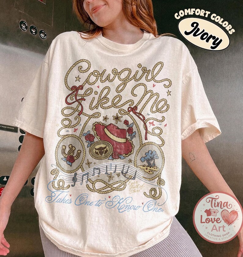 Pu&ograve; includere: Una t-shirt a maniche corte color avorio con una stampa grafica con il testo Cowgirl Like Me e Takes One to Know One. Il design include un cappello da cowboy rosso, un ferro di cavallo, un albero, note musicali e motivi a corda.