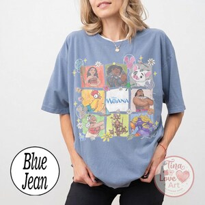 Puede incluir: Camiseta azul vaquero con una cuadr&iacute;cula de ilustraciones coloridas de personajes de la pel&iacute;cula de Disney Moana. La camiseta tiene cuello redondo y mangas cortas. La palabra "Moana" est&aacute; en el centro de la cuadr&iacute;cula.