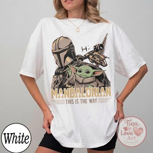Pu&ograve; includere: T-shirt bianco con grafica di The Mandalorian e Grogu, con la scritta "MANDALORIAN THIS IS THE WAY". Il design include un'astronave e un casco. La maglietta ha una vestibilit&agrave; ampia.