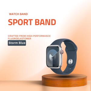 May include: A silver smartwatch with a storm blue sport band, displayed on a wooden stand. The watch face shows a blue and gray design. Text on the image reads "WATCH BAND SPORT BAND" and "Storm Blue".