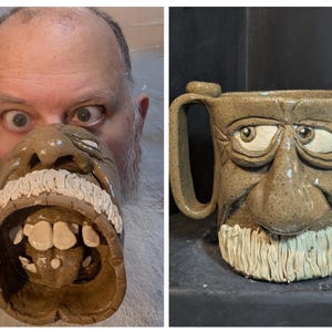 May include: A unique, handmade ceramic mug with a sculpted face design. The mug features a tan color with a white beard and teeth, and expressive eyes. The handle is integrated into the design. A fun and quirky addition to any mug collection.