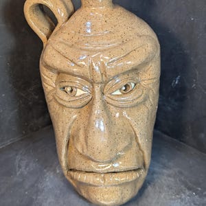 May include: A set of three ceramic mugs with a speckled, matte finish. The mugs are in shades of cream, light gray, and dark gray. Each mug has a simple, minimalist design, perfect for coffee or tea.