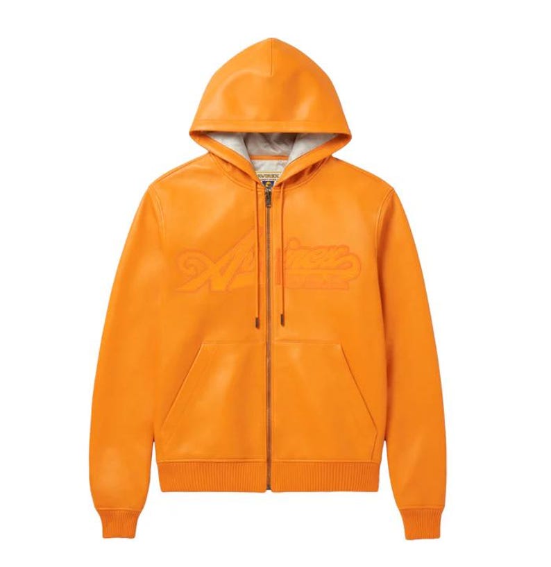 May include: Orange leather zip-up hoodie with a hood and front pockets. The hoodie features the embossed word "Aimer's" across the chest. The jacket has ribbed cuffs and hem, and a silver zipper.