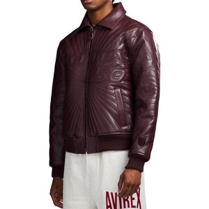 May include: A burgundy leather jacket with a quilted design and a zip-up front. The jacket features the text "VDP 50" on the chest and a small emblem on the sleeve. The jacket has a ribbed hem and cuffs.