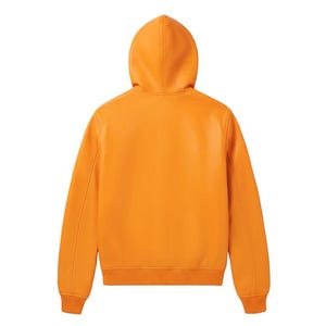 May include: Orange hooded jacket with a ribbed hem and cuffs. The back view of the jacket shows a smooth, solid color with a hood and long sleeves. The jacket is made of a leather-like material.
