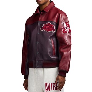 K&ouml;nnte beinhalten: Burgunderrote und dunkelburgunderfarbene Lederjacke mit Knopfleiste, Kragen und gerippten B&uuml;ndchen. Die Jacke hat einen Aufn&auml;her auf der Brust und die Nummer "75 25" auf dem rechten &Auml;rmel. Teil der Avirex-Kollektion.
