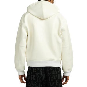May include: Cream-colored hooded sweatshirt with a white ribbed hem and cuffs. The back view shows a minimalist design with a hood and long sleeves. The sweatshirt is made of a soft, comfortable material.