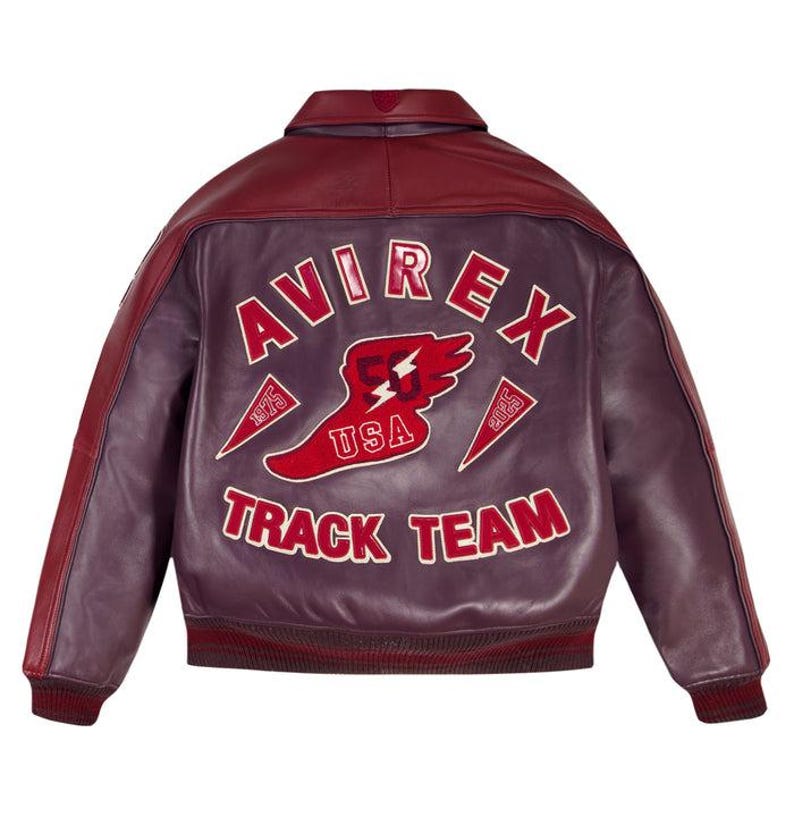 K&ouml;nnte beinhalten: Burgunderrote und violette Lederjacke mit dem Text "AVIREX TRACK TEAM USA" in wei&szlig;en Buchstaben. Die Jacke hat ein rotes Blitz- und Fl&uuml;geldesign mit gerippten B&uuml;ndchen und Kragen.