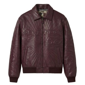 May include: A burgundy leather jacket with a ribbed collar, cuffs, and hem. The jacket features a zip-up front and the text "Avirex 50" embossed on the chest. The design includes a sunburst pattern radiating from the text.