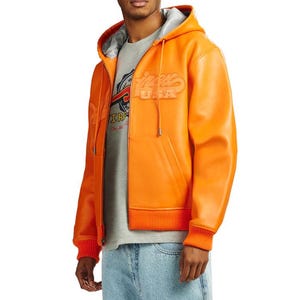 May include: Bright orange hooded jacket with a zip-up front, featuring the text "Winners USA" in a raised, stylized font. The jacket has a gray lining in the hood and a ribbed hem and cuffs. A gray t-shirt is visible underneath.