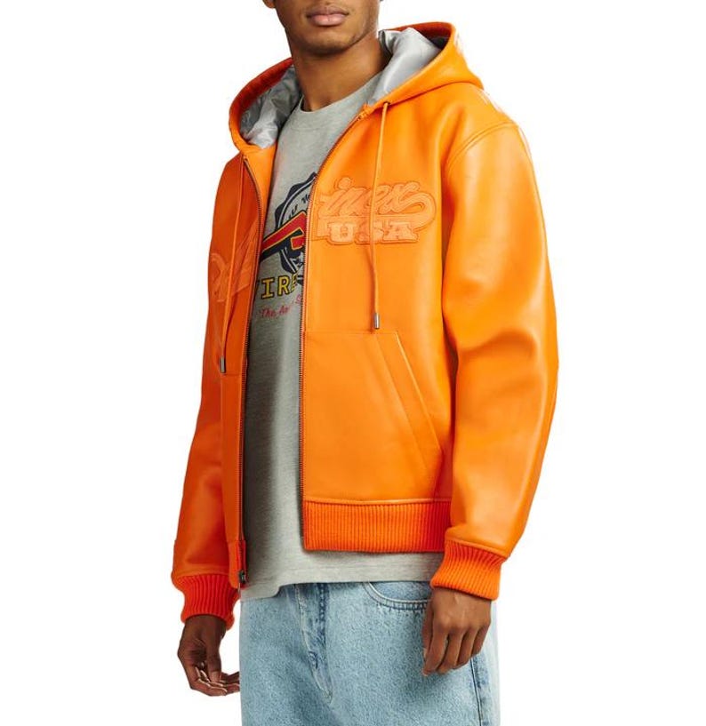 May include: Bright orange hooded jacket with a zip-up front, featuring the text "Winners USA" in a raised, stylized font. The jacket has a gray lining in the hood and a ribbed hem and cuffs. A gray t-shirt is visible underneath.