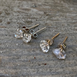 May include: Three pairs of silver stud earrings with clear quartz crystals. The crystals are faceted and have a natural, raw look.