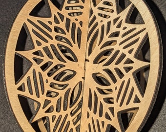 Può includere: Un ornamento natalizio in legno con un motivo a fiocco di neve tagliato al laser. L'ornamento è di colore marrone chiaro e presenta un motivo delicato e intricato.