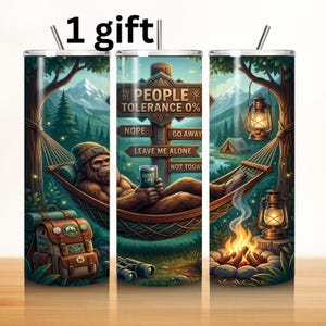 May include: A cylindrical tumbler featuring a graphic of a brown creature in a hammock, a campfire, and a wooden signpost with the text PEOPLE TOLERANCE 0%, NOPE, GO AWAY, LEAVE ME ALONE, NOT TODAY, and a mug labeled QUIET LIFE.