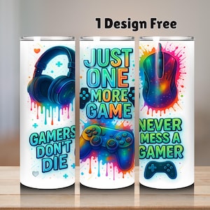May include: White tumbler with vibrant gaming graphics. Depicts a headset, mouse, and controller, alongside the phrases "Gamers Don't Die," "Just One More Game," and "Never Mess a Gamer." Includes the text "1 Design Free."