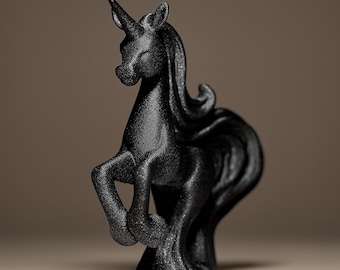 May include: A black unicorn figurine with a textured surface. The mythical creature is posed with its front legs raised, showcasing a detailed mane and a prominent horn. The sculpture is set against a neutral background.