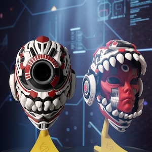 May include: Two futuristic masks in red, white, and black. One features a large circular lens, the other a red face design. They are displayed on yellow stands, offering a striking, tech-inspired aesthetic. The design suggests a sci-fi theme.