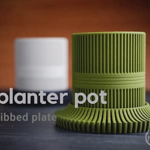 Peut inclure: Pot de jardinière vert avec un design nervuré et une base de plaque nervurée assortie. Le texte "planter pot" et "ribbed plate" est affiché sur l'image. Un pot cylindrique blanc est en arrière-plan.