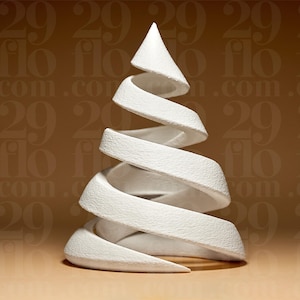 Könnte beinhalten: Eine weiße, abstrakte Skulptur in Form eines Weihnachtsbaums. Das Design zeigt eine spiralförmige, bandartige Form mit einer konischen Spitze. Die Skulptur hat eine strukturierte Oberfläche.