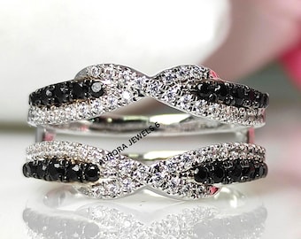 May include: A silver ring with a double band design. The top band features a row of small, sparkling white stones and a row of black stones. The bottom band mirrors the design. The text "AURORA JEWELS 6" is visible.