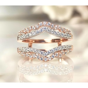 May include: Rose gold ring guard with a double-band design. Each band features a row of small, sparkling white gemstones. The ring guard is designed to be worn with another ring, enhancing its appearance.