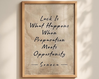 May include: A framed wall art print featuring a light brown, textured paper background with the black text: Luck Is What Happens When Preparation Meets Opportunity — Seneca. The frame is made of light-colored wood with a simple, clean edge.