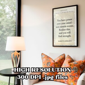 Puede incluir: Un cuadro enmarcado con una cita de Marco Aurelio: "Tienes poder sobre tu mente, no sobre los acontecimientos externos. Date cuenta de esto y encontrar&aacute;s la fuerza". El cuadro cuelga sobre un sill&oacute;n blanco con cojines florales naranjas.