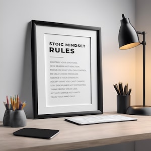 Może przedstawiać: Czarna oprawiona grafika z tekstem "STOIC MINDSET RULES" na drewnianym biurku. Czarna lampa biurkowa, oł&oacute;wki i notatnik r&oacute;wnież się tam znajdują. Tekst wymienia zasady stoickiego nastawienia.